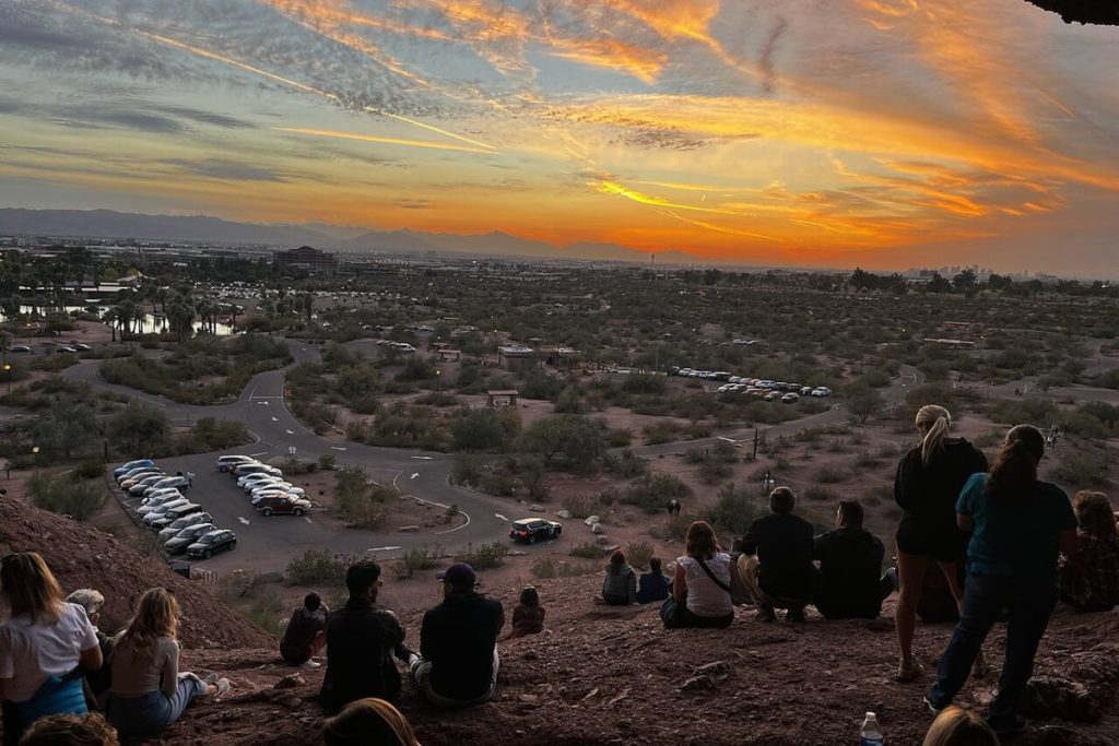 A group of people watch the sunset at Hole-in-the-Rock.
